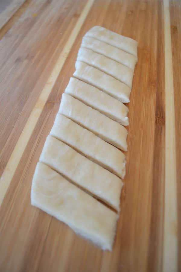 A wooden cutting board, with pieces of dough