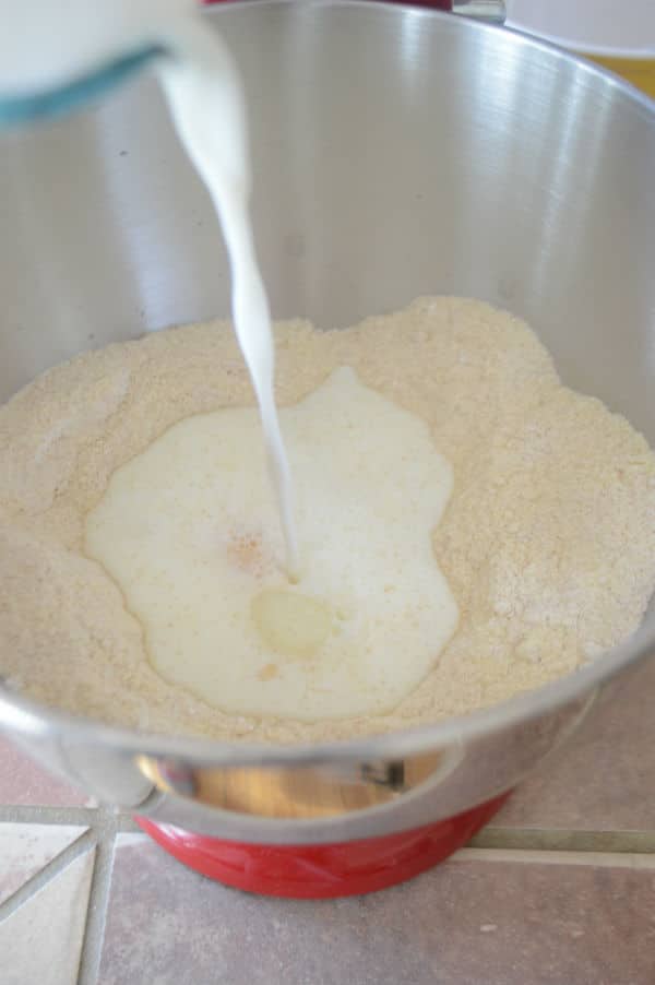 A metal bowl showing a mixture and pouring milk