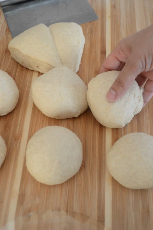 A wooden cutting board, with Bread dough and hand