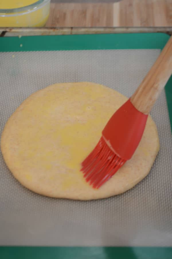 A close up of round dough on a paper sheet