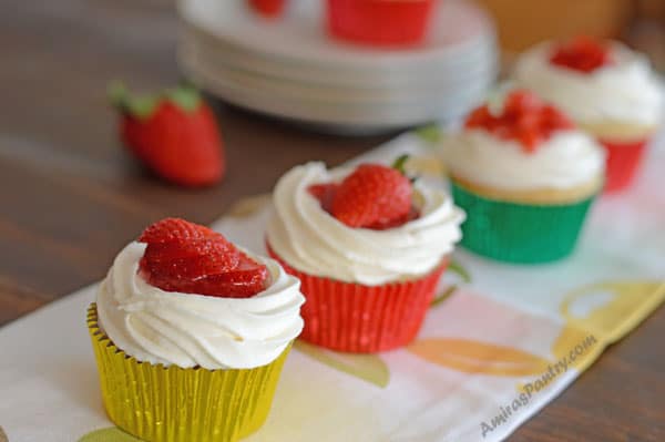 A close up of a cup cakes on a plate with strawberries