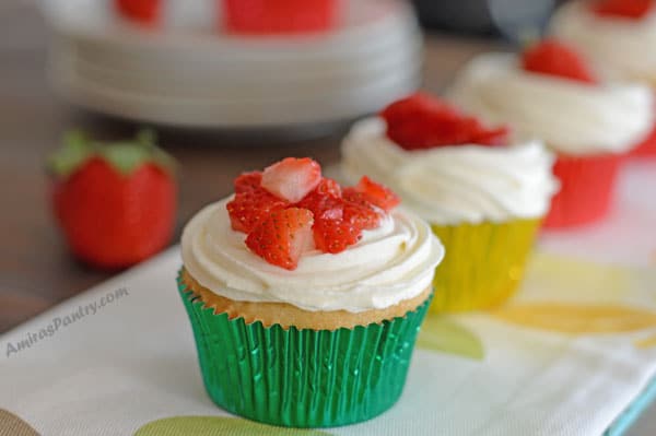 A close up of cupcake on a table with strawberry and frosting