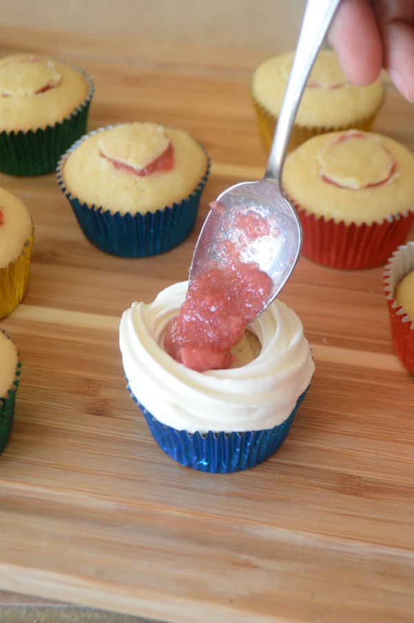 A wooden board with a Cupcake, spoon and Strawberry