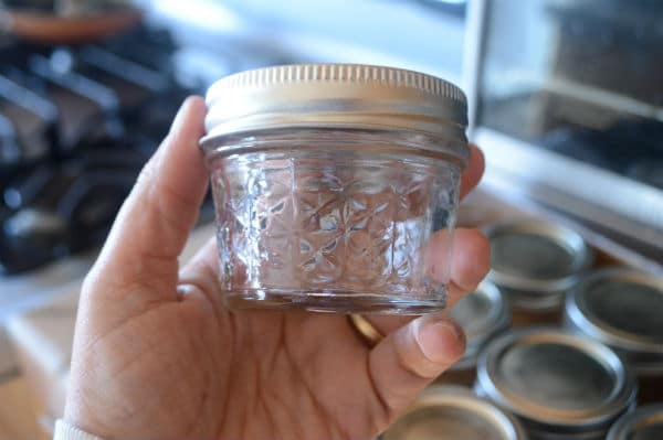 An empty glass container held by a hand