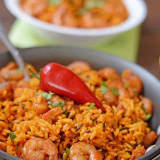 A dish is filled in food, with yellow Rice and spicy shrimp
