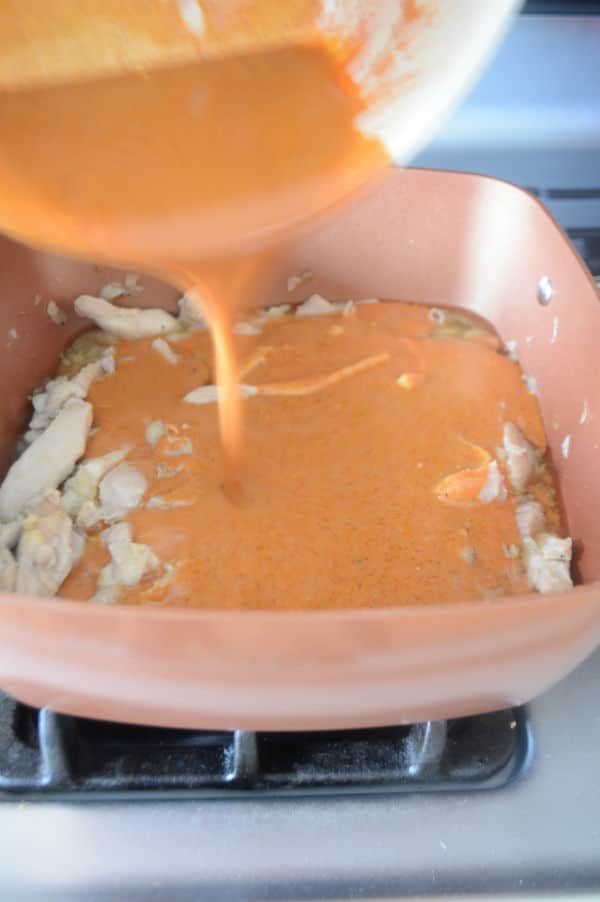 A pan of food on a stove with pouring mixture