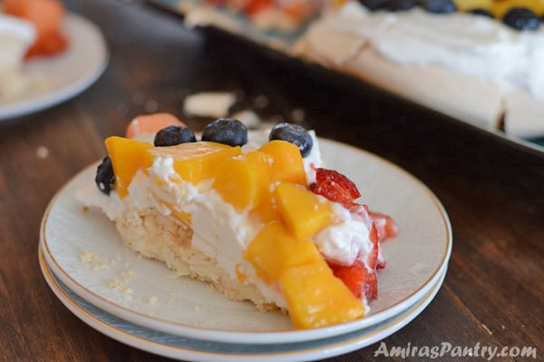 A plate of food with a slice of cake on a table, with Cream and fruits