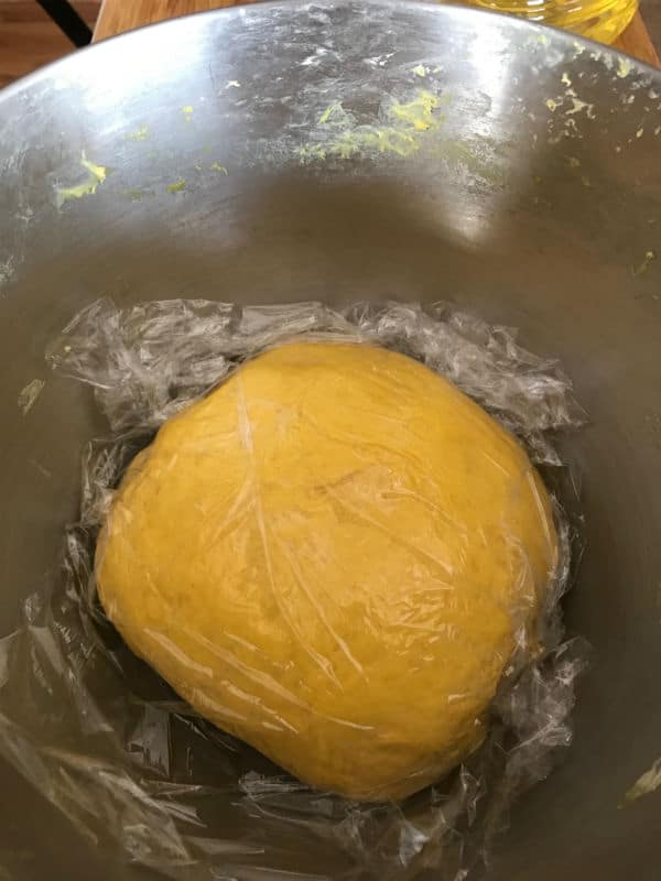 A close up of a dough in a bowl wrapped in plastic