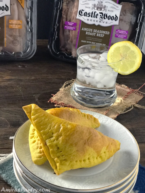 A close up of a folded dough with stuffing and a cup with drink