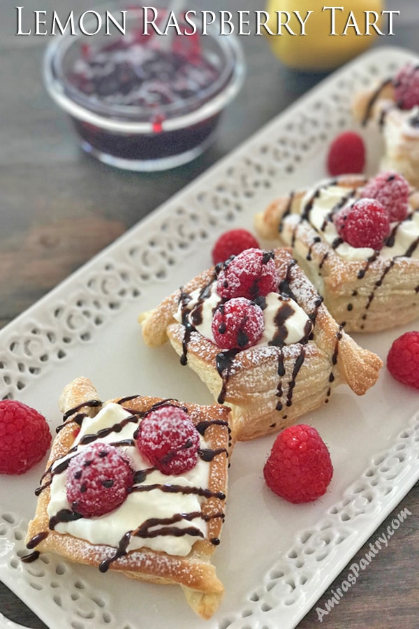 A close up of a lemon raspberry tart on a plate with berries