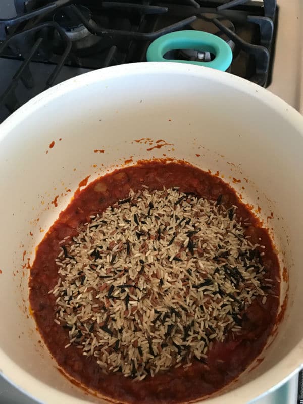 Wild rice being added to the pan with the other ingredients 