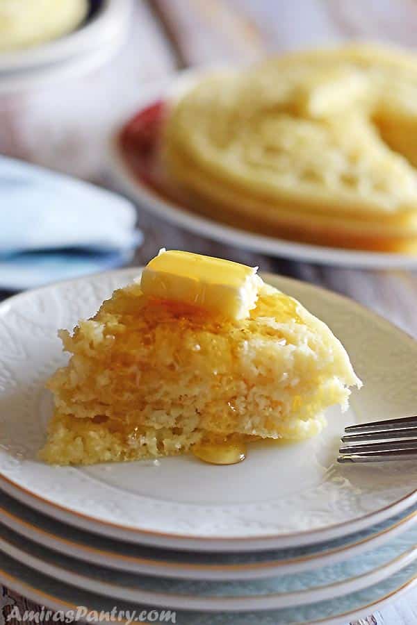  Une pile de crêpes marocaines coupées et posées sur une assiette blanche avec du beurre et du miel.