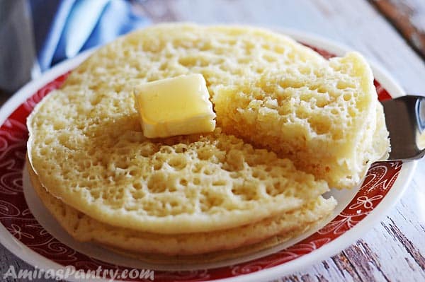 A serving of Moroccan pancakes being cur on a white plate with a red rim.