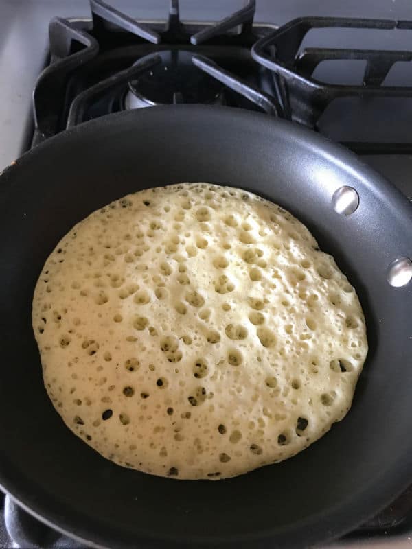 Step 3 of making Moroccan baghrir, cooking the pancakes in a skillet.