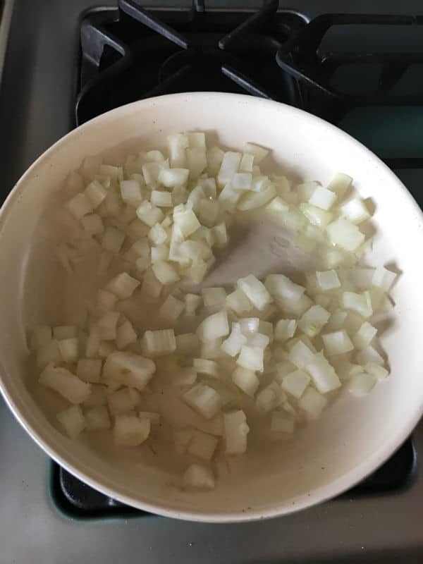 A bowl of food on a stove, with Onions