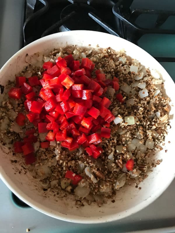 A pan of food on a stove, with Onions and vegetables