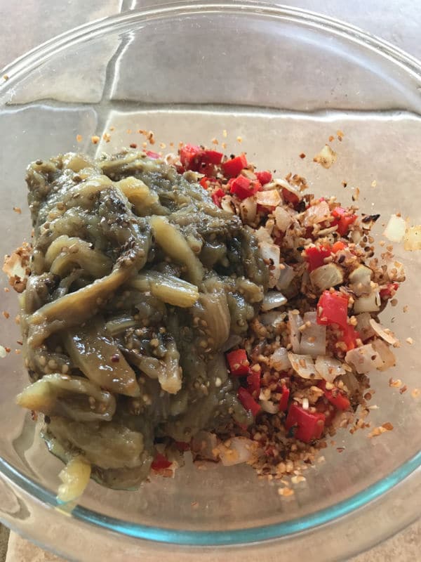 A bowl of food, with Onions, vegetables and eggplant