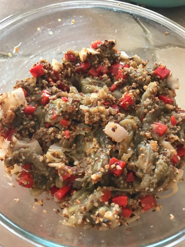 A bowl of food, with Onions, vegetables and eggplant mixture