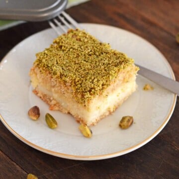 a maamoul piece on a white plate garnished with crushed pistachios.