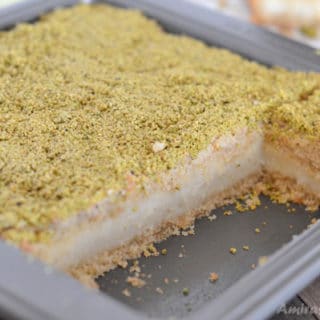 A piece of cake in a pan with maamoul mad pistachios