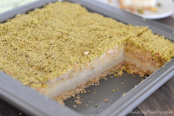 A piece of cake in a pan with maamoul mad pistachios