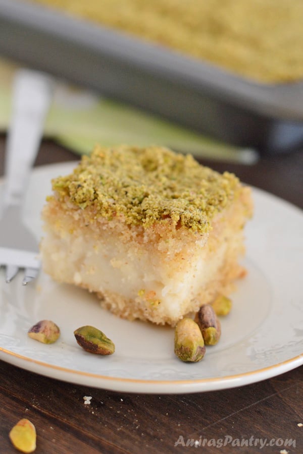 Un trozo de pastel en un plato, con sémola y pistacho