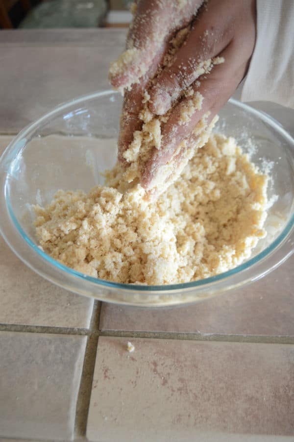 A hand mixing dough in a bowl