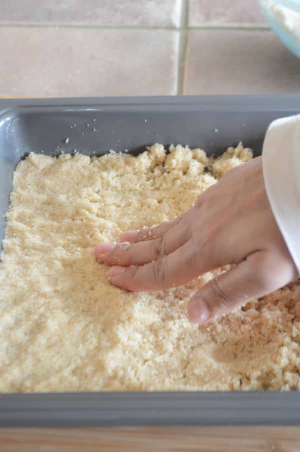 A hand mixing dough in a pan