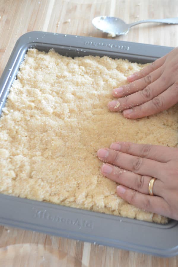 A hand mixing dough in a pan