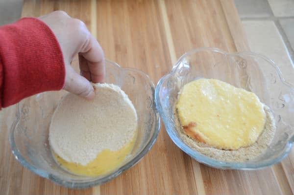 A hand mixing bread with eggs in a bowl