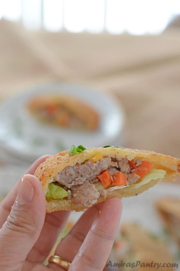 A hand holding an open sandwich with stuffing