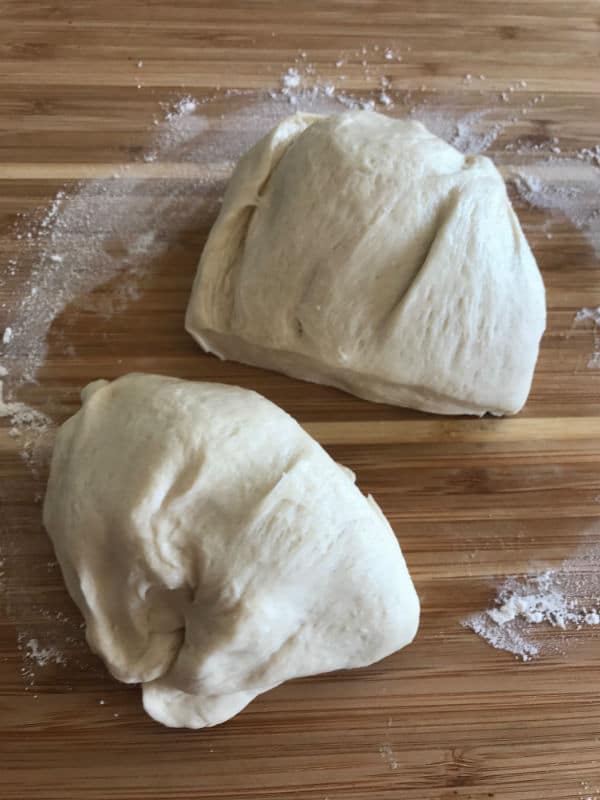 A photo showing two pieces of dough on a wooden table