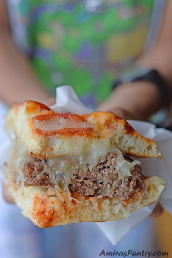 Little Hands holding a quarter of the pizza burger ready to be eaten.