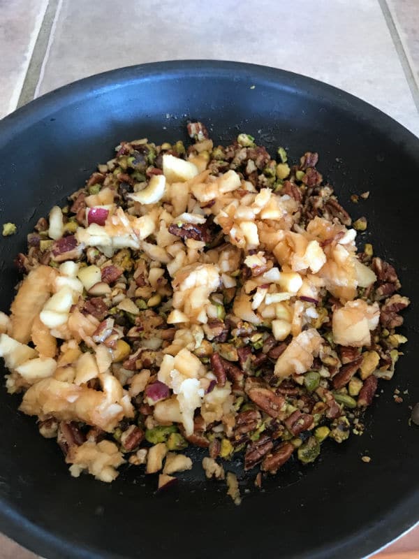 A bowl filled with apple and nuts over a stove