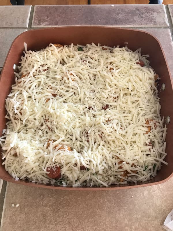 A close up for a pot with vegetables, rice, cheese and meat