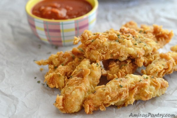 A close up of food on a table, golden chicken strips and dip