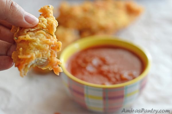 A close up of golden chicken strips and sauce dip