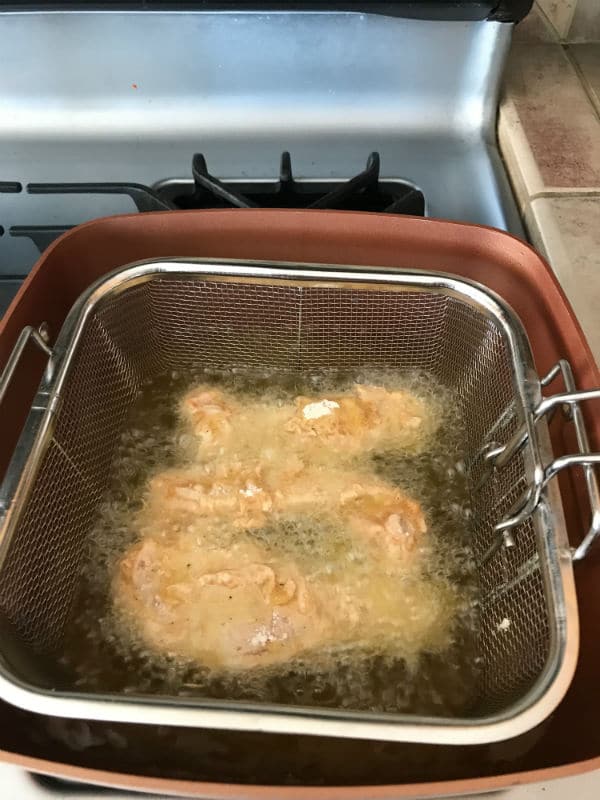 A stove top oven while frying chicken inside