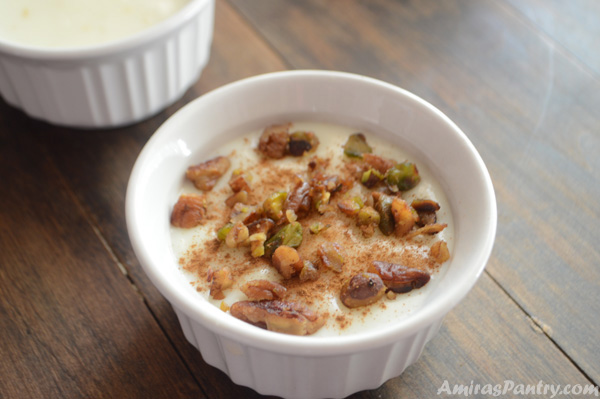 A cup of food on a table, with Rice pudding and nuts