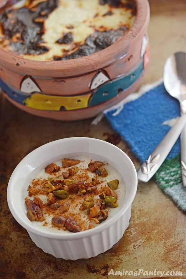 A cup of food on a table, with Rice Pudding and nuts