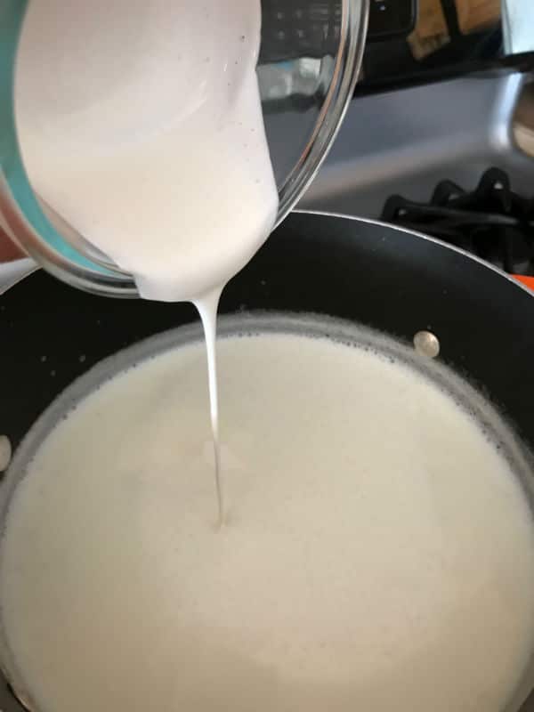 A close up of a bowl of milk on a stove, with Rice pudding