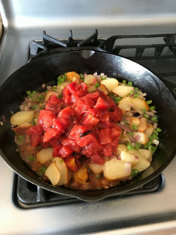 A pan filled with vegetables cooking on a stove, with Egg and Potato
