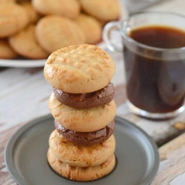 A close up of cookies on a plate nd a cup of coffee