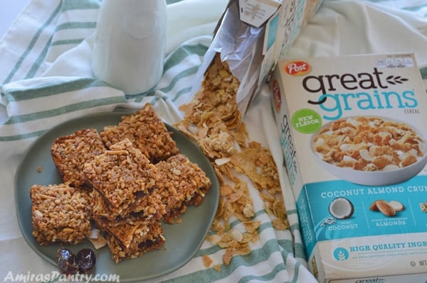 A plate full of breakfast squares with great grains cereal boxes on the side and a bottle of milk.