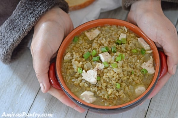 Hand holding a boel of freekeh soup.