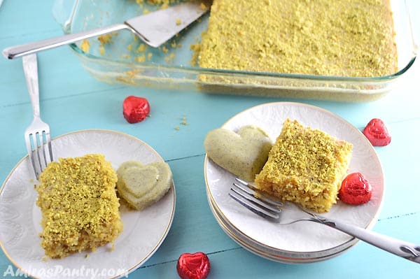 A plate of food with a slice of cake on a table, with Pistachio and Chocolate