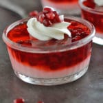 A glass cup on a table filled with pomegranate parfaits