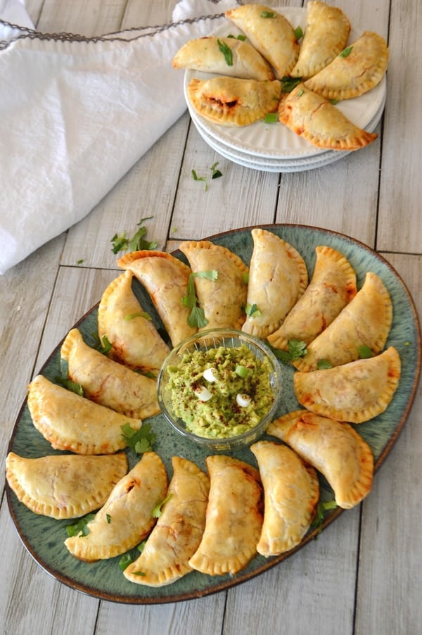 A photo of Empanadas sitting on a plate on a wooden table