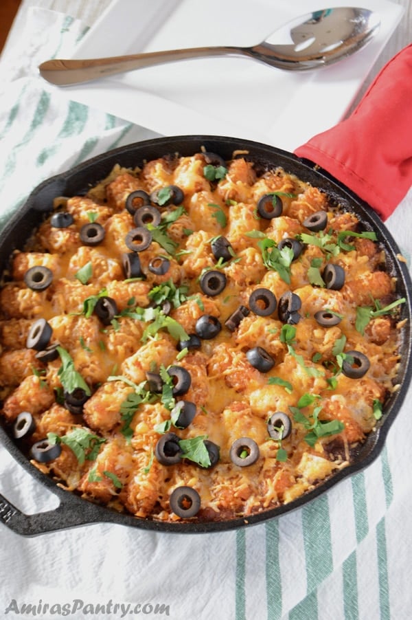 A pan with Tater tots, cheese and olives