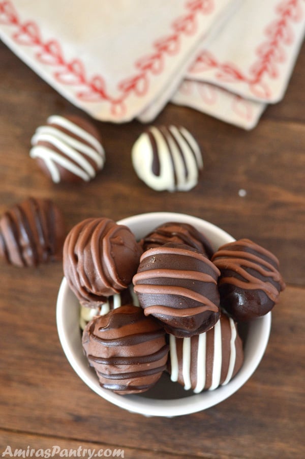 Chocolate Chip Cookie dough truffles in a white bowl with some truffles on the table